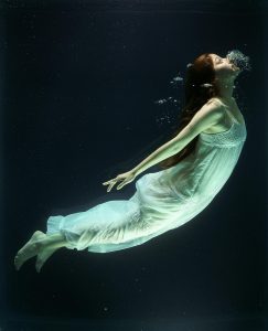Frau atmet aus unter Wasser